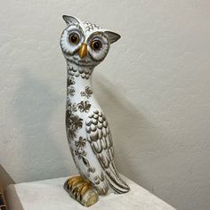 an owl figurine sitting on top of a white table next to a wall