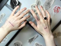 two hands with small tattoos on their fingers