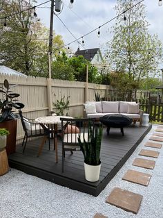 an outdoor patio with seating and potted plants on the deck area, surrounded by graveled stepping stones