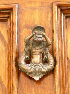 a door knocker with a statue on it's face and hands in the air