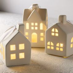 three lit up houses sitting on top of a carpeted floor next to each other