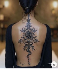 the back of a woman's neck with flowers and snakes tattooed on her body