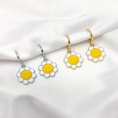 "This listing is for one pair of rhodium plated (silver color) or gold plated smiley face daisy flower charm earrings with mini huggie hoops. Earrings are about 1\" in total length." Cute Silver Flower Earrings, Trendy Silver Flower Drop Earrings, Daisy Shaped Earrings For Summer, Daisy-shaped Earrings For Summer, Trendy Everyday Flower Earrings, Trendy White Sterling Silver Hoop Earrings, Everyday Daisy Earrings, Trendy Smiley Face Jewelry For Summer, Cute Silver Hoop Earrings