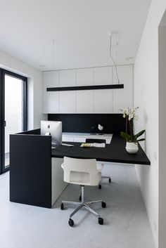 a black and white office desk in an empty room with a potted plant on it