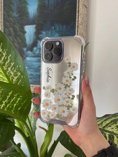 a woman holding up her phone case with daisies on it