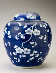 a blue vase with white flowers painted on the front and bottom, sitting on a table