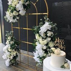 a white wedding cake sitting on top of a table next to a tall metal arch