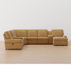 a brown leather sectional sofa sitting on top of a hard wood floor next to a white wall