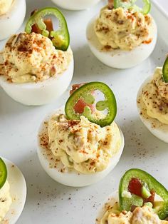 deviled eggs stuffed with cheese and peppers on a white platter topped with seasoning