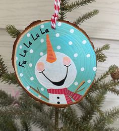 a christmas ornament hanging from a tree with a snowman face on it