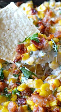 a tortilla topped with corn and bacon is being held by a tortilla chip