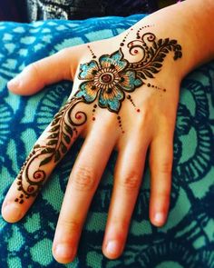 a woman's hand with hennap on it and blue flowers in the middle