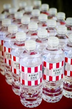 rows of empty water bottles lined up on a red tablecloth with white and red striped labels