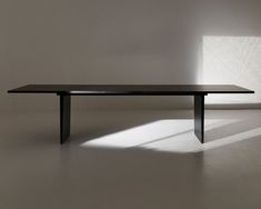 a black table sitting in the middle of a room with sunlight coming through the window