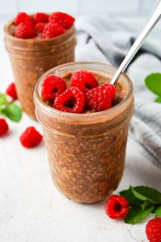 two jars filled with raspberries and oatmeal on top of a table