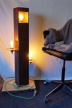 a chair with a blanket on it next to a tall wooden pillar that has two lit candles in it