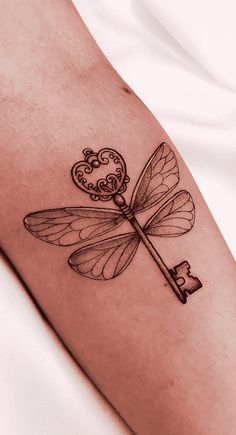 a dragonfly with a key tattoo on it's leg