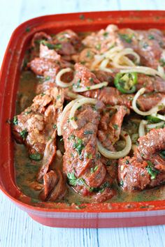 a red casserole dish filled with meat and noodles