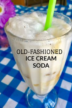 an old - fashioned ice cream soda with a green straw in it on a blue and white checkered tablecloth