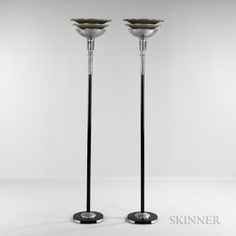 two tall metal candlesticks sitting next to each other