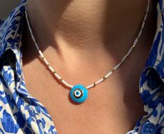 A handmade Evil Eye Necklace that is made from white glass beads, gold metal parts and a really special round evil eye that is made from light blue enamel. I have created this necklace at 39 cm length and it's slightly adjustable with the extension chain at the joined edges. Find it only at Christina Christi Store. 👉  My Women Necklaces Collection: https://etsy.me/3J2FcEi MATERIALS - White Beads from Glass. - Metal parts in Gold Color. - Evil Eye is made from Enamel. DIMENSIONS - Blue Evil Eye Gold Beaded Necklaces With Evil Eye For Gifts, White Round Pendant Necklace With Evil Eye, White Evil Eye Round Pendant Necklace, Adjustable White Beaded Necklace With Evil Eye, Bohemian White Necklace With Evil Eye Detail, White Bohemian Necklace With Evil Eye, White Bohemian Beaded Necklace With Evil Eye, Bohemian White Beaded Necklace With Evil Eye, Bohemian White Evil Eye Necklace