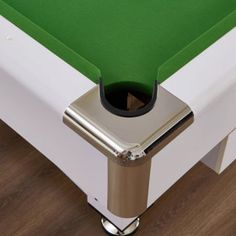 a pool table with a green cloth on the top and silver base, in front of a wooden floor