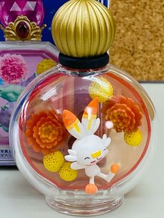 a glass bottle with an orange and yellow flower decoration on top of it next to a box