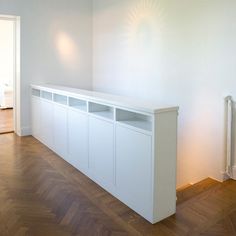 an empty room with white furniture and wood flooring