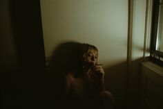 a woman sitting on the floor in front of a window brushing her teeth with an electric toothbrush