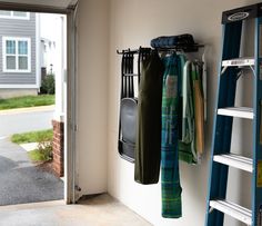 there is a blue ladder next to the door and some clothes hanging from it's hooks