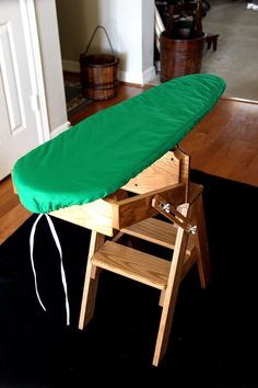 an ironing board with a green cover sitting on top of it next to a step stool