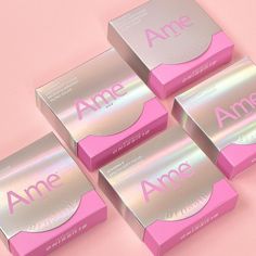 four pink and silver boxes with the word ame written on them, sitting on a pink surface