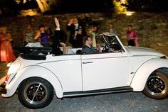 a group of people in an old fashioned car waving to the camera while others look on