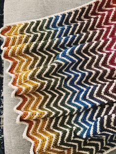 a multicolored knitted blanket laying on top of a table