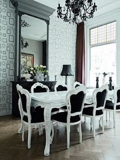 a dining room table with black chairs and a chandelier hanging from the ceiling