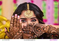 a woman with henna on her face and hands covering her eyes while she holds her hand up to her face