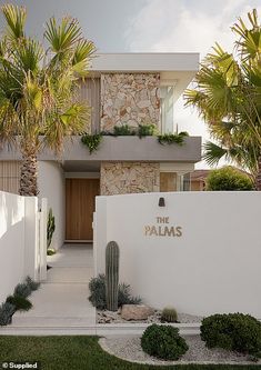 a white house with palm trees in front of it and the words the palms written on the wall