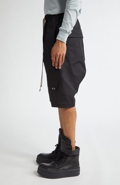 Angluar cargo pockets bring signature Rick Owens edge to these stretchy cotton cargo shorts. 36" inseam; 32" leg opening; 13 1/2" front rise; 17 1/2" back rise (size 50EU) Elastic/drawstring waist Cargo bellows pockets 97% cotton, 3% elastane Hand wash, line dry Made in Italy Designer Clothing Utility Bermuda Bottoms With Built-in Shorts, Utility Style Bottoms With Cargo Pockets, Utility Style Cargo Shorts, Utility Style Shorts With Cargo Pockets, Knee-length Streetwear Shorts With Pockets, Knee-length Utility Cargo Bottoms, Utility Cargo Style Bermuda Bottoms, Utility Cargo Bermuda Bottoms, Utility Cargo Shorts With Multiple Pockets