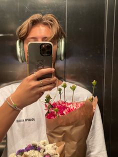 a person taking a selfie with flowers and headphones