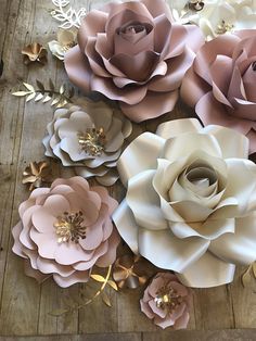 large paper flowers are arranged on a wooden surface with gold leaves and petals in the center