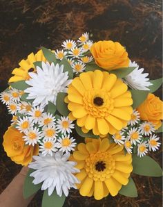 a bouquet of yellow and white flowers in someone's hand