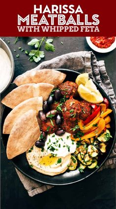 a plate with meatballs, vegetables and pita bread on it next to some dipping sauce