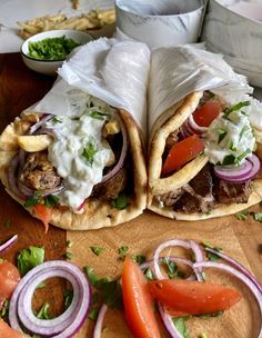 two burritos with meat and vegetables on a cutting board