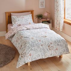 a bed in a bedroom with pink walls and wooden flooring next to a window