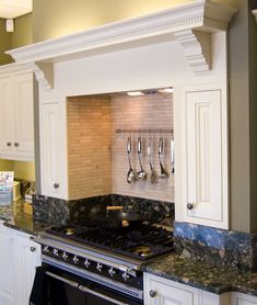 a stove top oven sitting inside of a kitchen next to white cabinets and counter tops