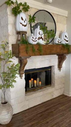 a fireplace decorated for halloween with pumpkins, candles and greenery on the mantle