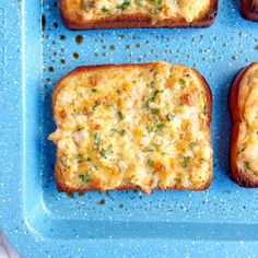 four pieces of bread with cheese and herbs on them sitting on a blue tray,