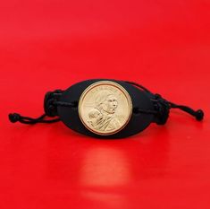 You are looking at a genuine leather bracelet with an authentic US 2000 ~ 2008 Sacagawea Dollar BU Uncirculated Coin, showing OBVERSE in front - Sacagawea and Her Infant Son. You need to pick a year from pull-down menu. The obverse design, by Glenna Goodacre, depicts the young Shoshone woman, Sacagawea, portrayed in three-quarter profile. In the Shoshone verbal legend, Sacagawea is described as having large dark eyes, a feature included in this portrait relief. On her back, Sacagawea carries her Adjustable Black Bracelet For Collectible, Adjustable Black Bracelet For Collectors, Sacagawea Dollar, Uncirculated Coins, Genuine Leather Bracelet, Coin Bracelet, Leather Wristbands, Wristband Bracelet, Lewis And Clark