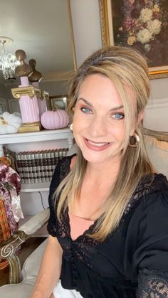 a woman sitting in a chair smiling at the camera with blue eyes and blonde hair