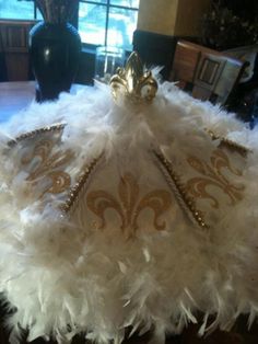 a white and gold feather crown sitting on top of a table